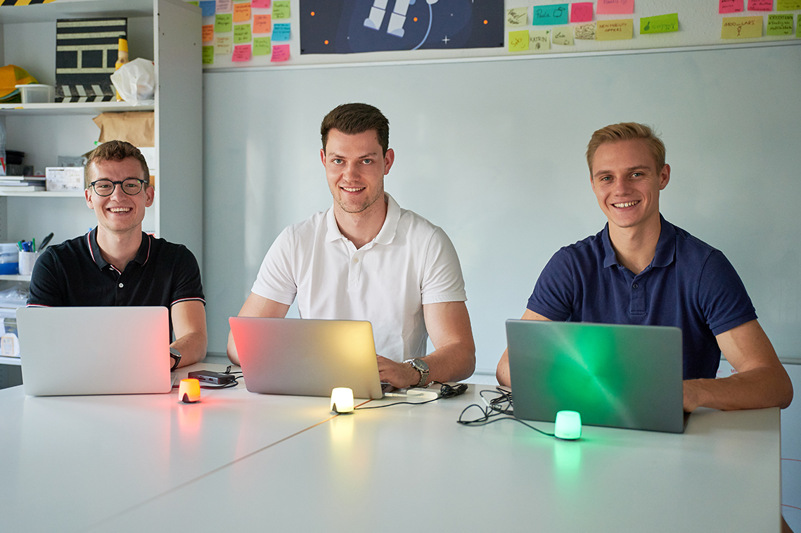 Drei Studenten mit Laptops an einem Tisch