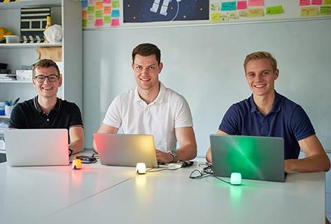 Three students with laptops at a table